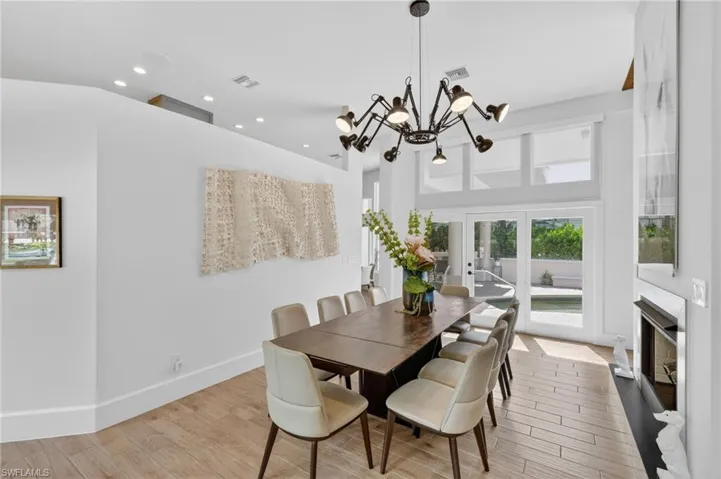 Spacious dining area featuring high ceilings, light wood-look flooring, and a fireplace with a white mantel