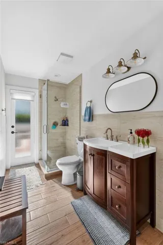 This bathroom features a dark wood vanity with a white countertop and a clear glass shower enclosure
