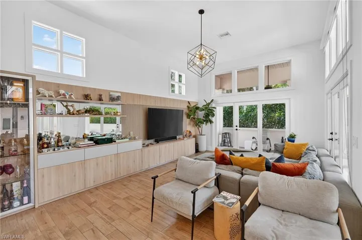 Spacious living area featuring high ceilings, large windows, and light wood flooring