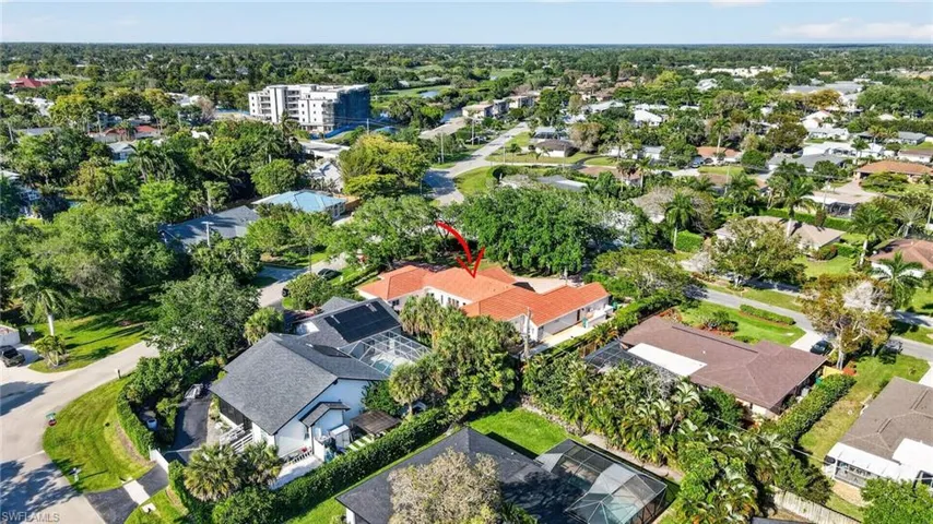 The property features a red tile roof and is surrounded by lush green trees
