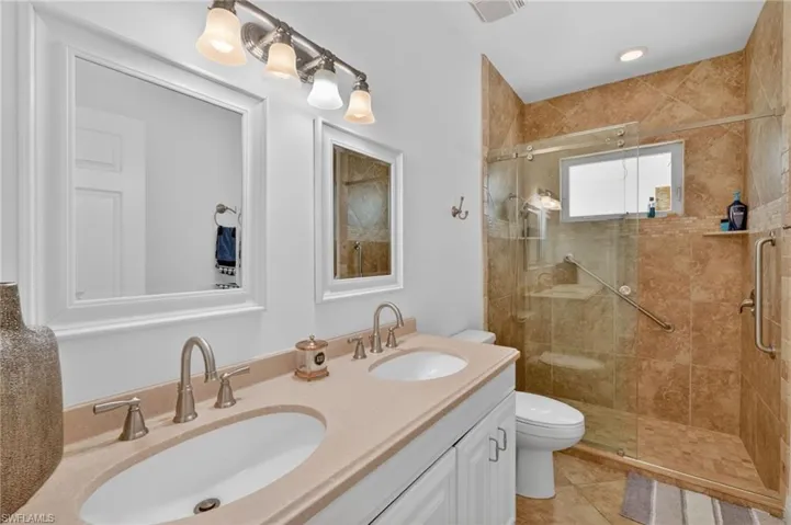 Bathroom featuring a double vanity with light-colored countertops, dual sinks, and two framed mirrors
