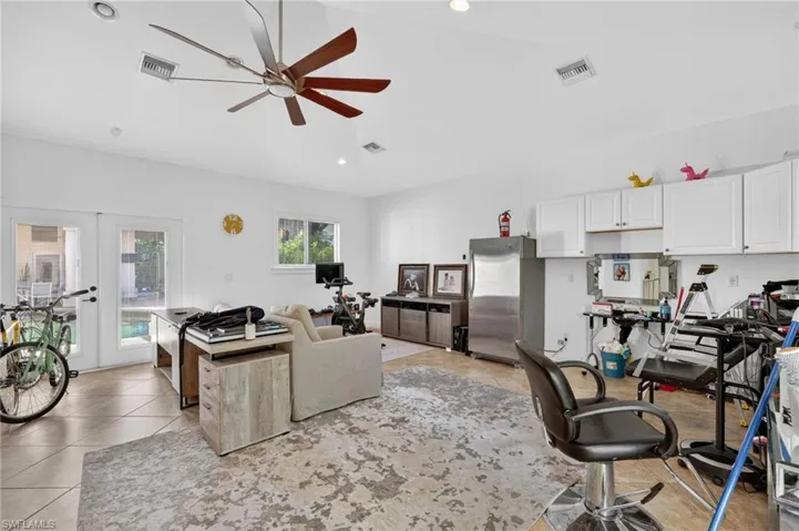 This spacious room features vaulted ceilings with a ceiling fan, recessed lighting, and tile flooring