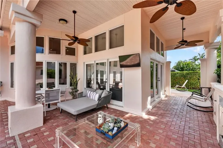 Expansive covered patio featuring brick paving, ceiling fans, and a variety of windows and glass doors