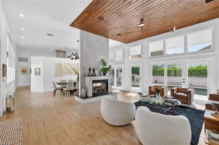The property features a bright and spacious living area with light wood flooring and a distinctive wood-paneled ceiling