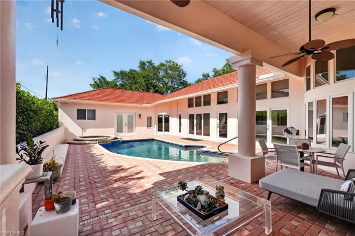 The property features an outdoor pool with an adjacent spa, surrounded by a brick patio