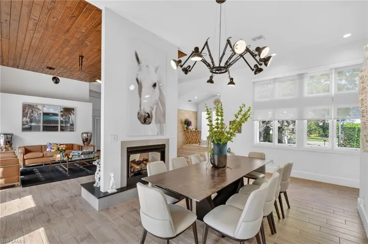 Dining area featuring light wood flooring, a modern chandelier, and large windows with privacy blinds