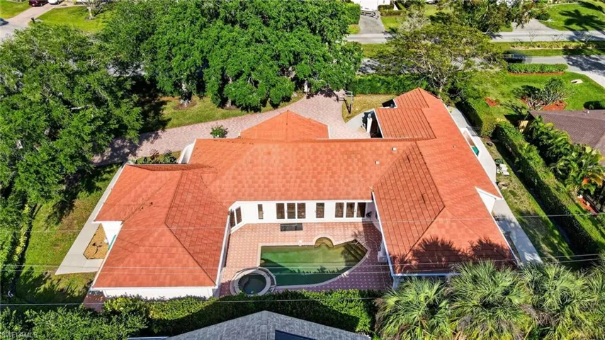 This property features a red tile roof, a swimming pool, and a paved patio area