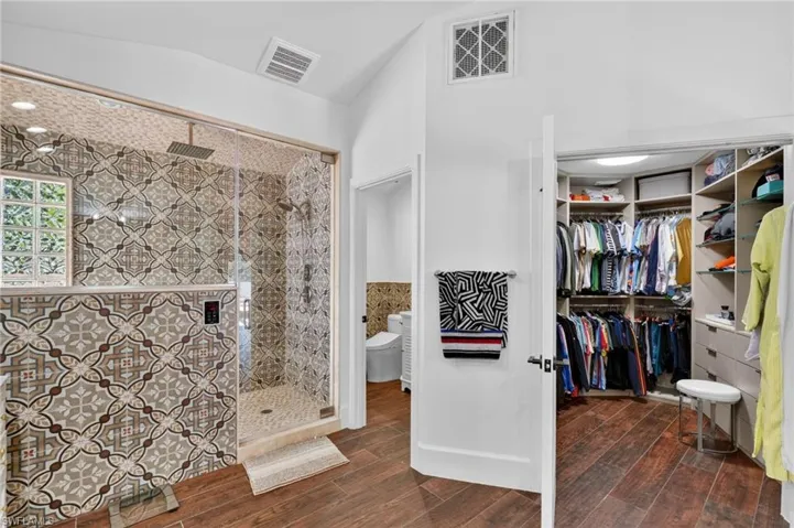 The bathroom features a spacious walk-in shower with patterned tile, a rainfall showerhead, and a glass enclosure