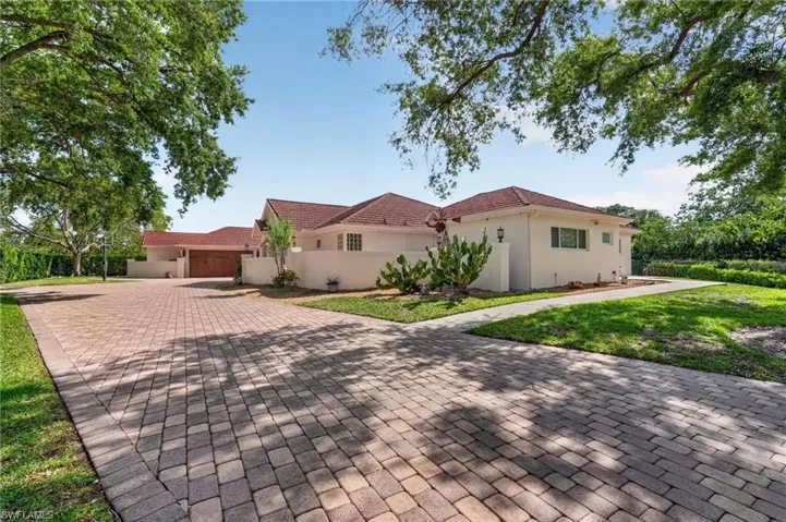 The property features a spacious paver driveway, a stucco exterior, and a red tile roof