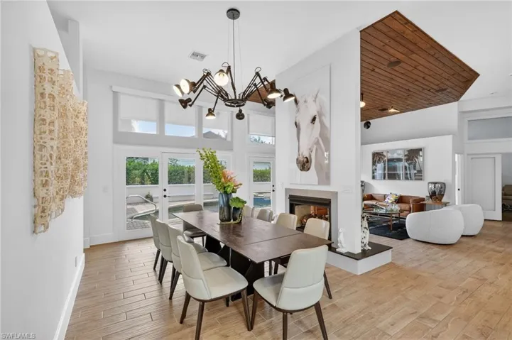 The dining area features a unique modern chandelier, a dark wood dining table with seating, and light-colored tile flooring