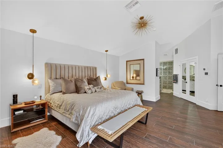 The property features wood-look tile flooring, vaulted ceilings, and contemporary light fixtures