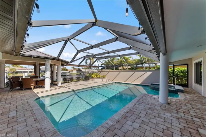 Integrated pool / hot tub with a patio, a sunroom, a lanai, and outdoor dining area