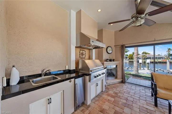 Kitchen featuring a textured wall, dark countertops, white cabinetry, ceiling fan, and stainless steel refrigerator