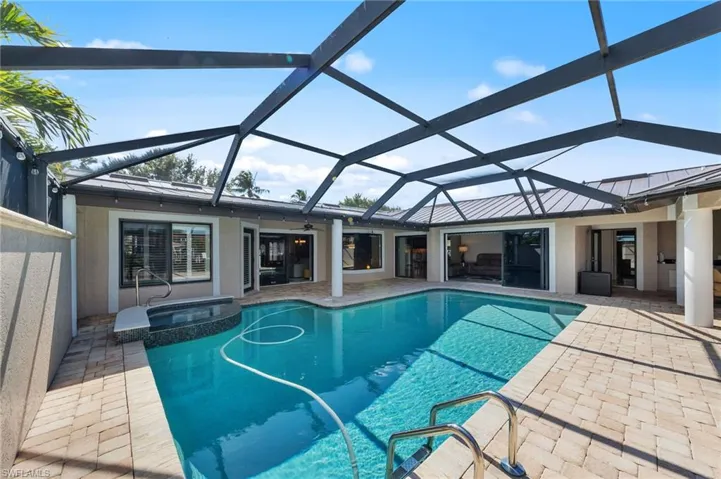 Relaxing pool / spa featuring a sunroom, glass enclosure, and a patio