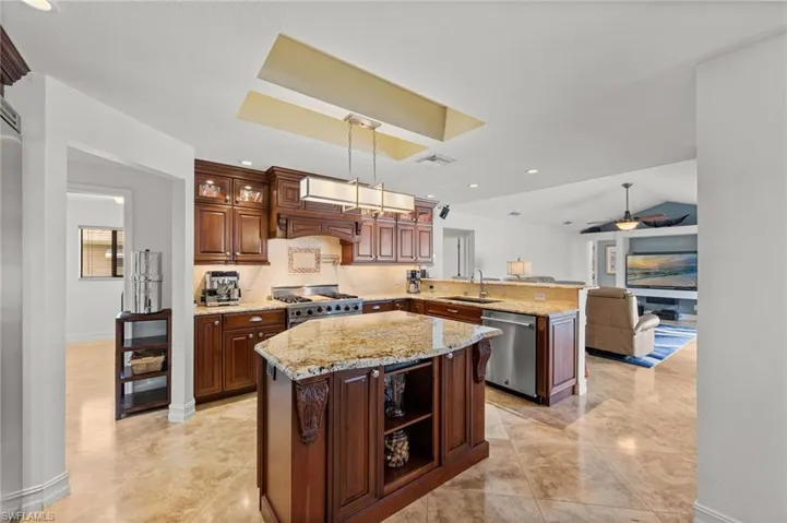 Kitchen with a peninsula, light stone countertops, open floor plan, stainless steel appliances, and open shelves