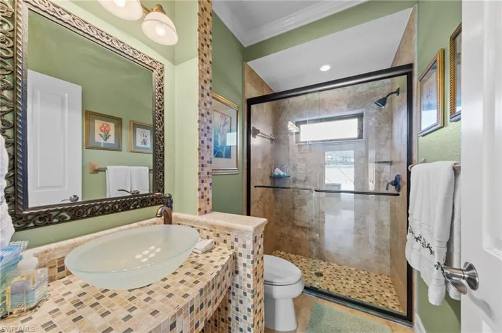 Full bathroom with vanity, a shower stall, and crown molding
