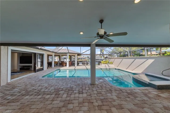 Outdoor pool with a patio, glass enclosure, an in-ground hot tub, and a sunroom