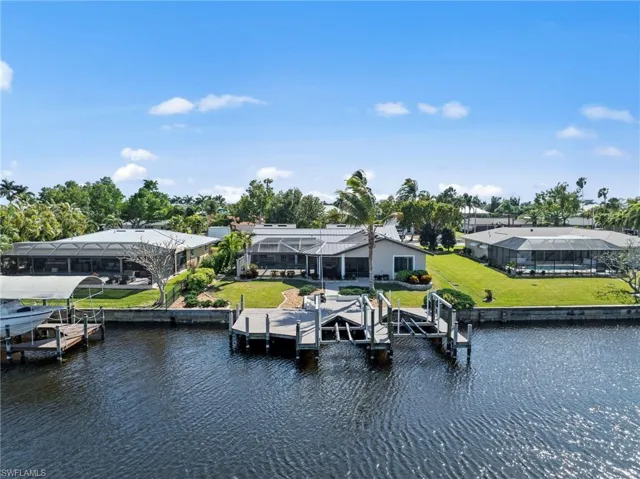 Dock area with boat lift, a water view, and a yard
