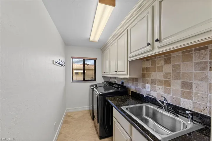 Laundry room featuring cabinet space, washer and clothes dryer, a textured wall, and light tile patterned floors