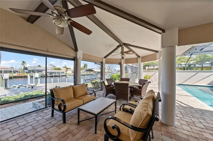 Sunroom / solarium featuring ceiling fan, lofted ceiling with beams, a patio area, and a residential view