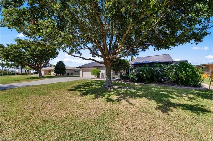 View of front of house with a front yard, driveway, a metal roof, and a garage
