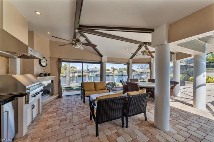 View of patio / terrace featuring a ceiling fan, an outdoor living / dining area, exterior kitchen, a water view, and a residential view
