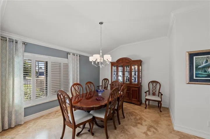 Dining area featuring ornamental molding, vaulted ceiling, and hanging lights