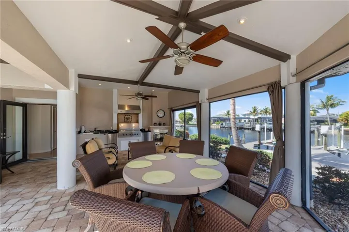 Dining area with beamed ceiling, a water view, recessed lighting, a ceiling fan, and stone finish floors