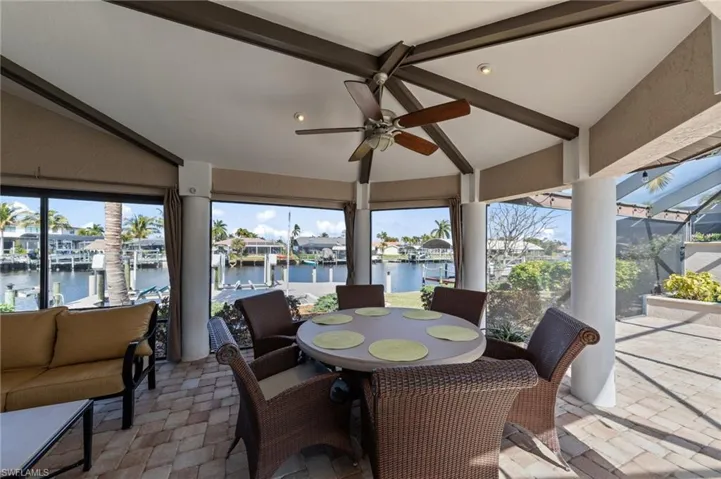 View of patio / terrace with ceiling fan, a water view, a sunroom, a residential view, and outdoor dining space