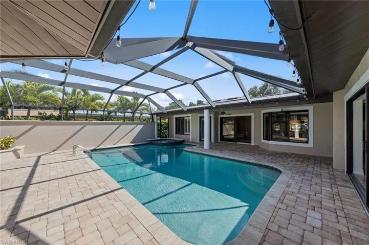 Relaxing pool / spa featuring glass enclosure, a patio, and a sunroom
