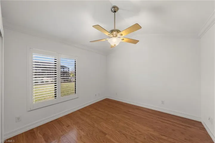 Unfurnished room featuring ornamental molding, lofted ceiling, wood finished floors, and ceiling fan