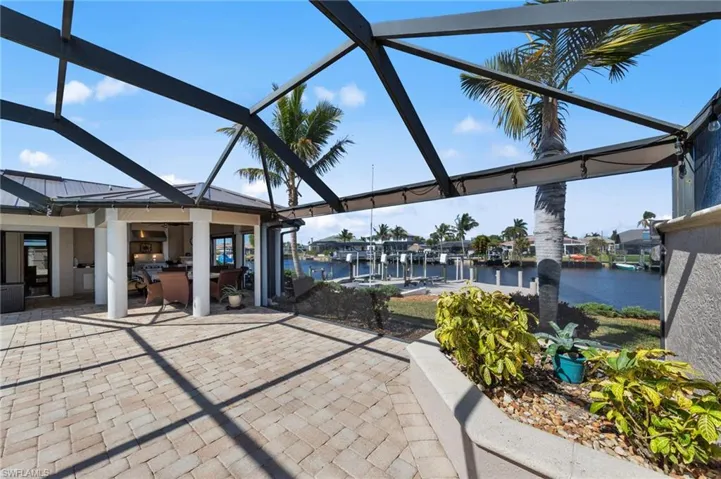View of patio with glass enclosure, a water view, a dock, boat lift, and a sunroom