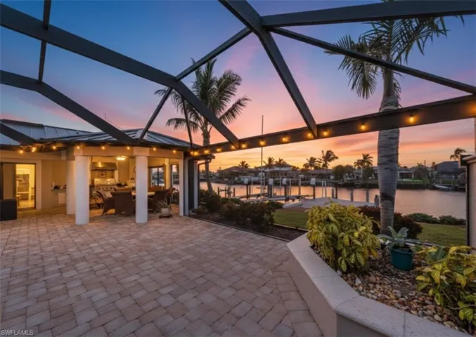 View of patio with glass enclosure, a water view, and outdoor dining area