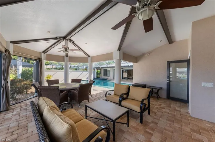 Sunroom / solarium featuring ceiling fan, outdoor dining space, a patio area, vaulted ceiling with beams, and plenty of natural light