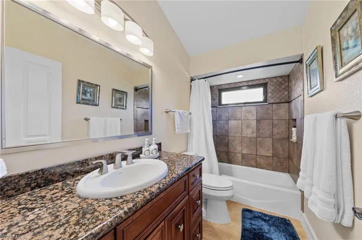 Bathroom with shower / bath combo with shower curtain, vanity, and light tile patterned floors