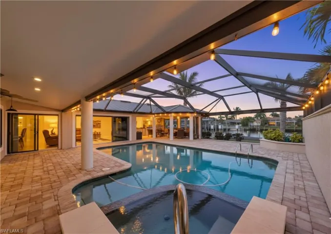Integrated pool / hot tub featuring a patio, a sunroom, and a lanai
