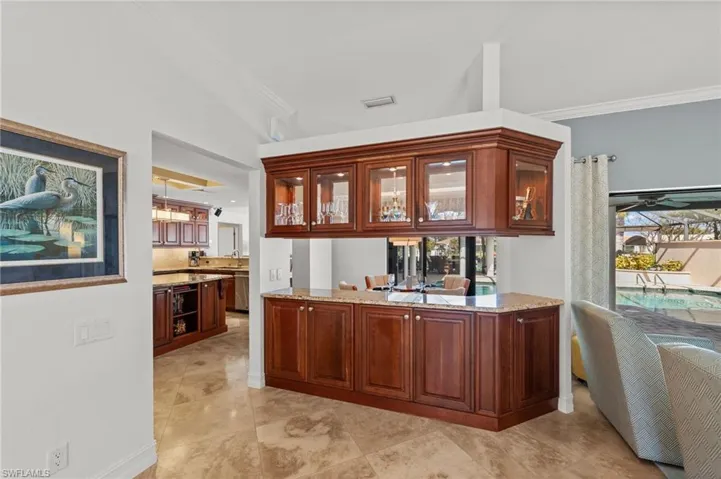 Bar with light stone countertops, glass insert cabinets, crown molding, and dishwasher