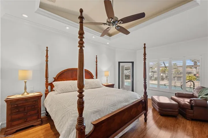 Bedroom with hardwood / wood-style flooring, a tray ceiling, crown molding, ceiling fan, and recessed lighting