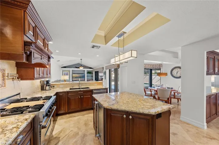 Kitchen featuring high end stainless steel range oven, light stone countertops, decorative light fixtures, backsplash, and open floor plan