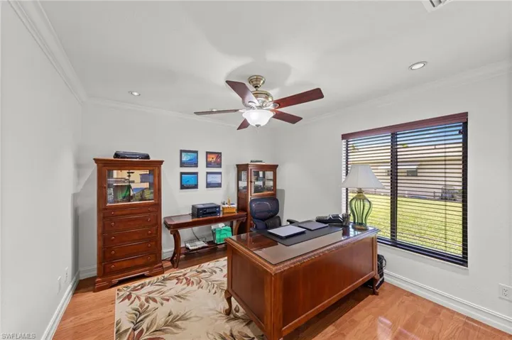 Office with light wood-style floors, ceiling fan, and crown molding