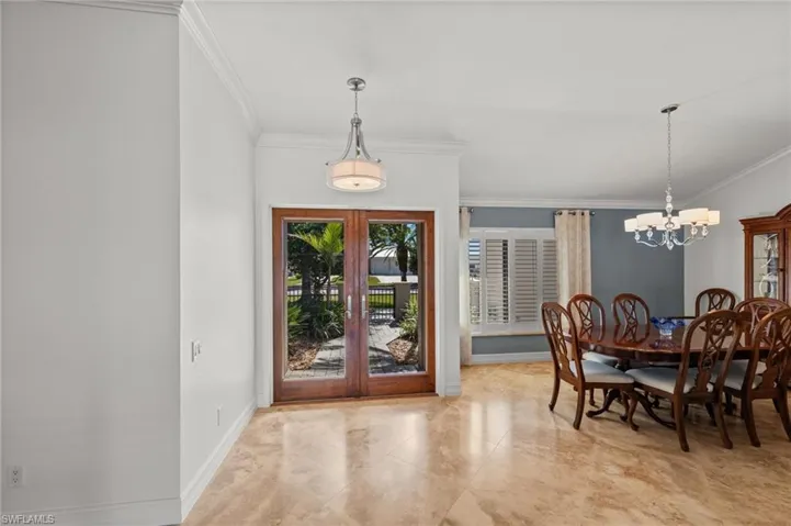 Dining area with french doors, crown molding, and a chandelier