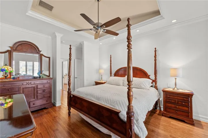 Bedroom featuring a tray ceiling, light wood-style flooring, a ceiling fan, ornamental molding, and recessed lighting