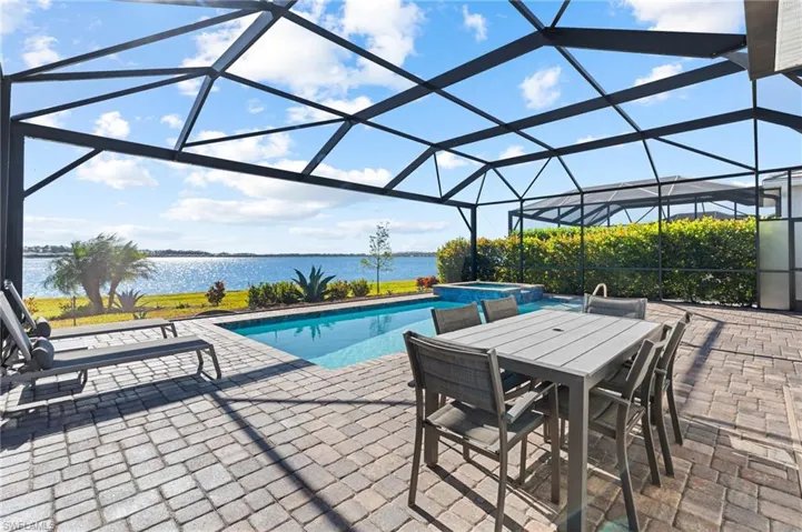 View of swimming pool with an in ground hot tub, a patio, a water view, and a lanai