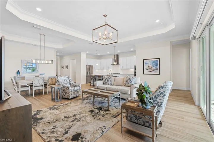 Living room with light wood-type flooring, a raised ceiling, and plenty of natural light