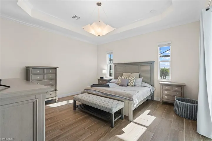 Bedroom with a tray ceiling, crown molding, and wood-type flooring