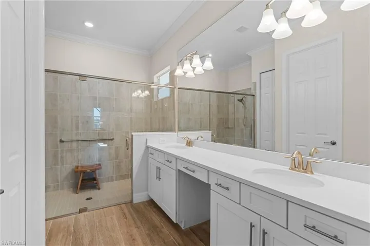 Bathroom featuring vanity, hardwood / wood-style flooring, an enclosed shower, and crown molding