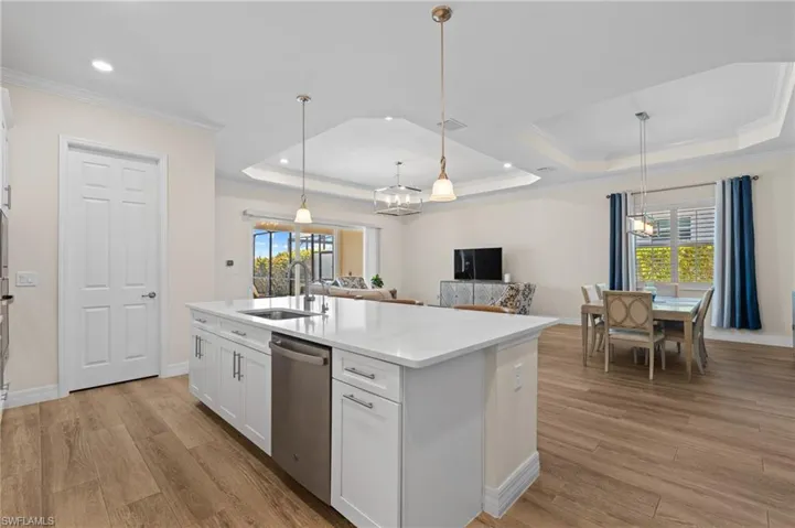 Kitchen with stainless steel dishwasher, plenty of natural light, white cabinets, and sink