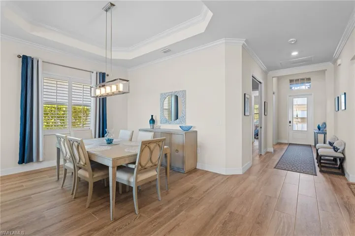 Dining area with a raised ceiling, light hardwood / wood-style floors, and ornamental molding