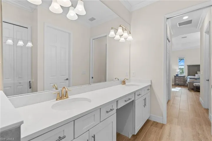 Bathroom with hardwood / wood-style floors, vanity, a shower with door, and ornamental molding
