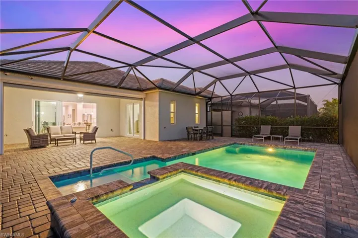 Pool at dusk with a lanai, outdoor lounge area, an in ground hot tub, and a patio area